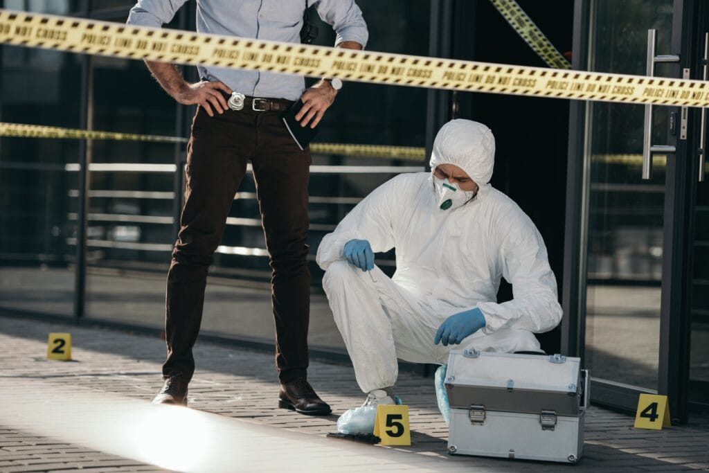 Male detective examining criminologist's work, focused on evidence and investigation details.